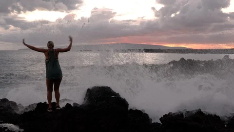 Silhouette of woman getting splashed by waves at sunset Vídeo Stock 120483751