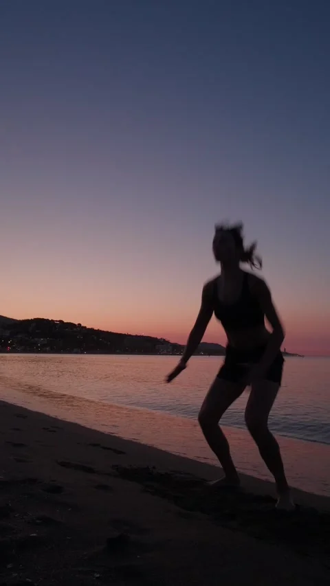 Silhouette woman performing dynamic deep squat on sandy beach at sunset, em.. Stock Footage 344688389