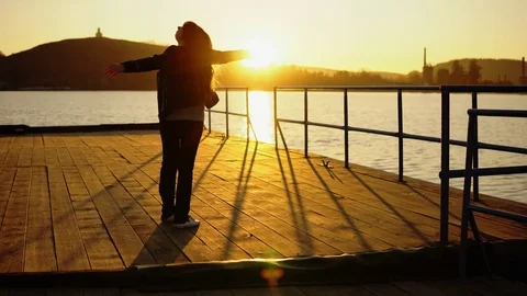 Silhouette of a woman on a pier in the rays of the setting sun Stock Footage 81204071