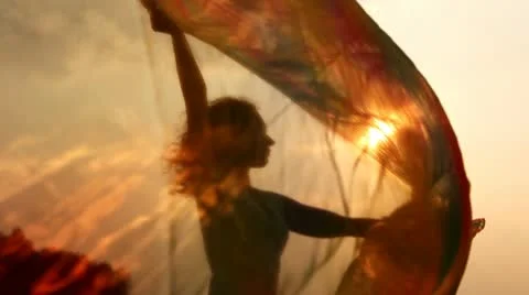 Silhouette of woman with thin shawl in hands which waves on wind Stock Footage 9601844