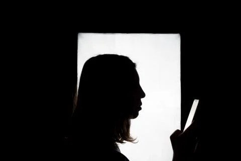 Silhouette of a woman using smart phone mobile. Stock Photos