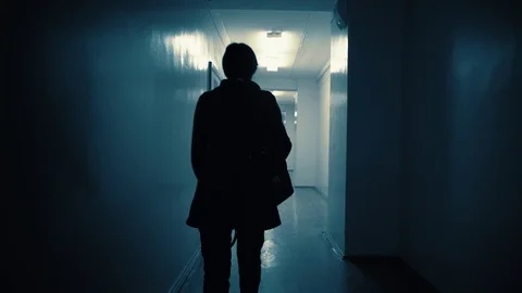 Silhouette of a woman walking down a dark corridor in the late evening. Stock Footage