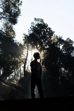 Silhouette of a young boy while sun rays coming from behind Stock Photos