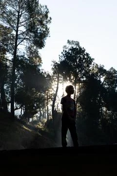 Silhouette of a young boy while sun rays coming from behind Stock Photos