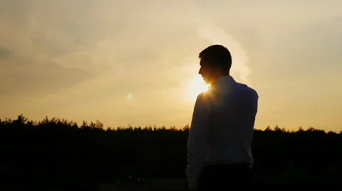 Silhouette of a young businessman talking on the phone. It stands on a sunset Stock Footage 66011663