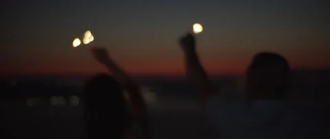 Silhouette of young couple celebrating while holding sparklers at sunset Stock Footage 136240486