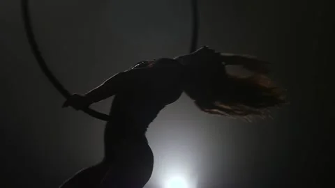Silhouette Young girl performs the acrobatic elements in the air ring. Slow Stock Footage 110665033