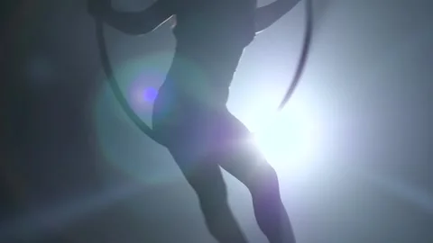 Silhouette Young girl performs the acrobatic elements in the air ring. Slow Stock Footage 110667547