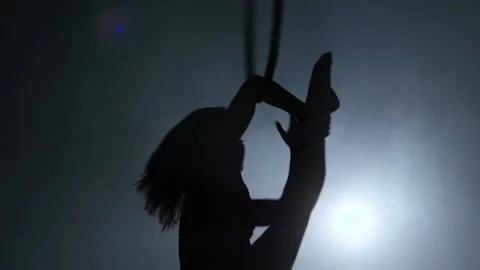 Silhouette Young girl performs the acrobatic elements in the air ring. Slow Stock Footage 110668355