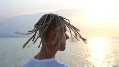Silhouette of a young guy with dreadlocks on his head near sea during sunset Stock Footage 101240271