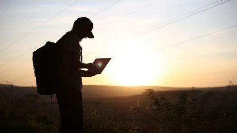 Silhouette of young guy on a hiking, using laptop for searching coordinates. Stock Footage 116721110