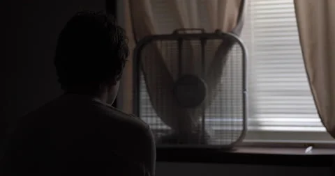The silhouette of a young high school aged teen boy sitting on his bed.

- Stock Footage 213838314