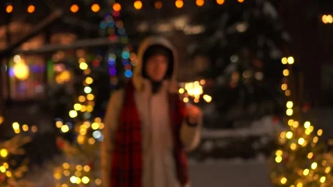 Silhouette of a young man in defocusing in a white jacket with burning sparklers Stock Footage 254769331