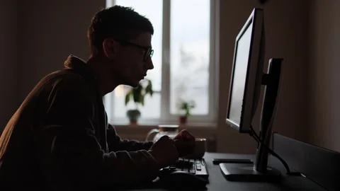 Silhouette of a Young Man in Glasses Using Computer in Dark Room for Learning Stock Footage 309205418