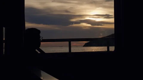 Silhouette of Young Man Sitting Inside Ferry Boat. Evening Seascape Light Stock Footage 266827370