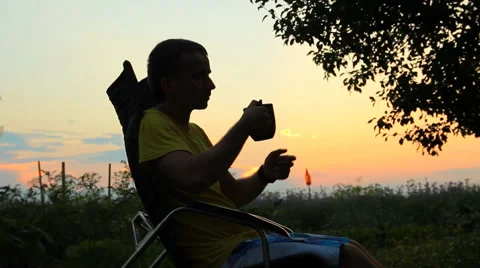 Silhouette of young man sitting on sunset or sunrise. Confident teenage boy Stock Footage 65093859