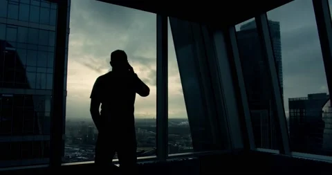 Silhouette of an young man that is talking at phone and walking inside the Stock Footage