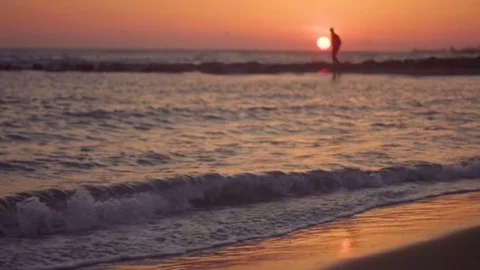 Silhouette of young man walking on the beach in beautiful sunset. Waves on the s Stock Footage 80438978