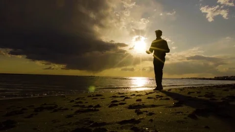 Silhouette of young man walking on the seaside in beautiful sunset. Landscape on Stock Footage 80438963