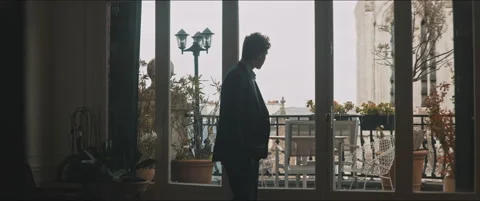 Silhouette of a young man walking by the window staring outside Stock Footage 203585756