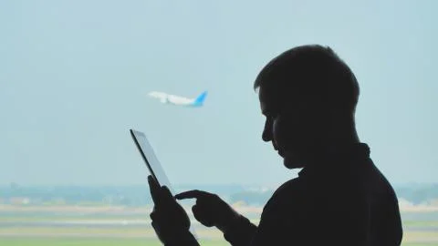 Silhouette of young men using tablet pc on the background of an airplane taking 스톡 사진