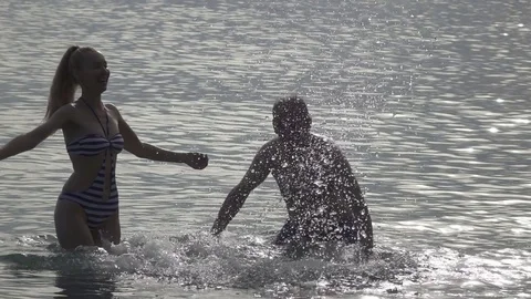 The silhouette of young people of the man and woman who stand in the sea and Stock Footage