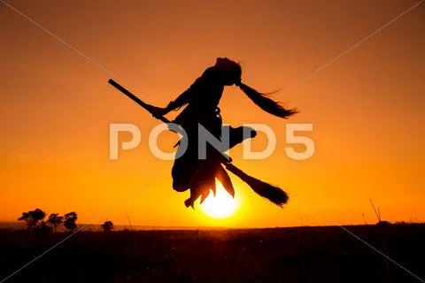 Silhouette of young witch flying on the broomstick Stock Photos