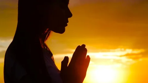 Silhouette of young woman praying at sunset Stock Footage