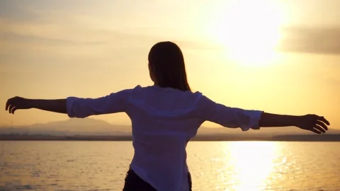 Silhouette of young woman spin at sunset on lake. Female figure dance at golden Stock Footage 89943853
