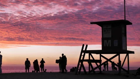 Silhouetted active beach at sunset near life guard tower Stock Footage 131474156