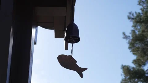 Silhouetted bell hangs by chain against clear blue sky Stock Footage 331702138