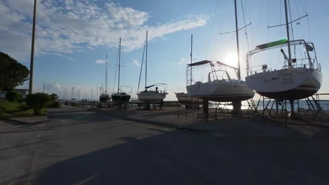 Silhouetted boats in shipyard with sunset backlight wide pan view Video stock 337459047
