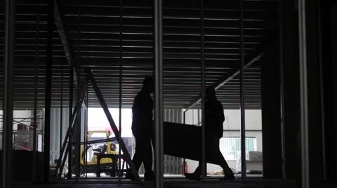 Silhouetted builders erect wall partition on a British construction site Vidéo 61934106
