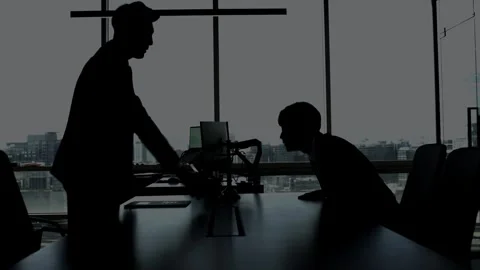 Silhouetted Businessmen Sitting at Desk Using Laptop 스톡 동영상 337994054