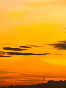 Silhouetted Clouds Against Bold Orange Sunset Gradient Sky 스톡 사진