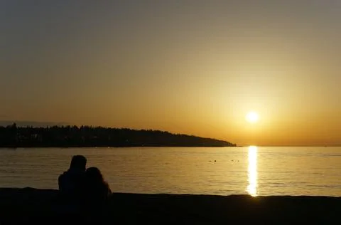 Silhouetted couple enjoying the sunset on the seashore Stock Photos