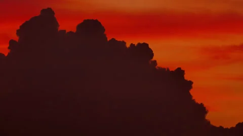 Silhouetted cumulus cloud morphing against vibrant sunset sky, time-lapse Stock Footage 346162464