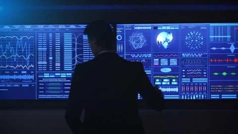 Silhouetted Figure Observing Multifaceted Data on a Large Screen Stock Footage 297538443