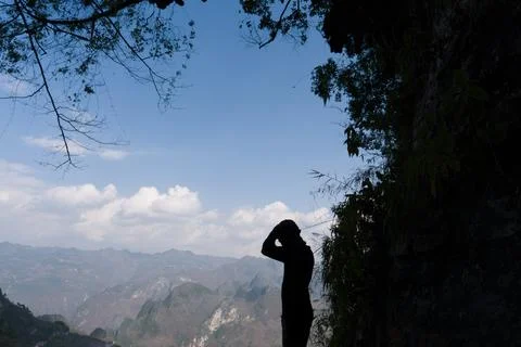Silhouetted figure stands on cliff's edge Stock Photos