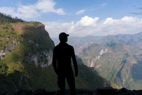 Silhouetted figure stands at cliff's edge Stock Photos