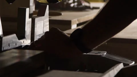 Silhouetted hands position a board at a miter saw Stock Footage 346255938