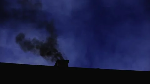 Silhouetted image of smoke drifting from a chimney into the dark sky Stock Footage 329912461