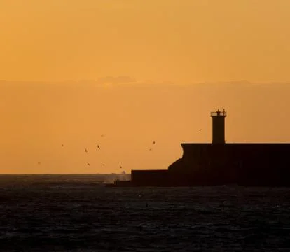 Silhouetted Lighthouse During a Sunset Stock Photos
