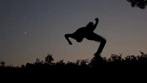 Silhouetted Man Performs Acrobatic Martial Arts Tricking Kick, Slow Motion Stock Footage 146563541