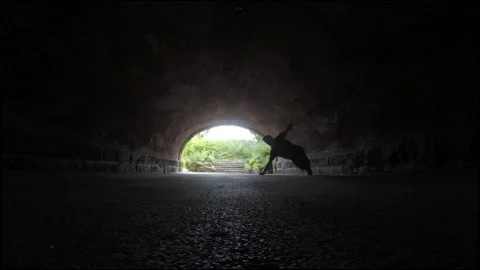 Silhouetted Man Performs Corkscrew Flip in Tunnel, Slow Motion Stock Footage 146557428
