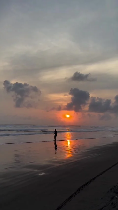 Silhouetted Man Walking on Reflective Wet Beach at Sunset Vidéo 339716457