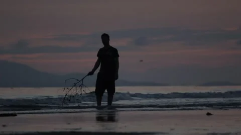 Silhouetted Man Walks on Beach Stock Footage 47001598