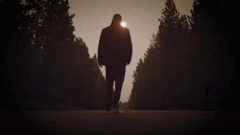 Silhouetted Man walks down abandoned road in red smoky morning Stock Footage 94352696