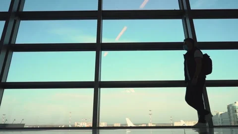 Silhouetted men in mask walking at arrival area of international airport Stock Footage 185651970