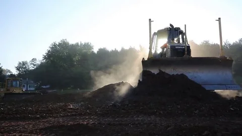 Silhouetted Mini Dozer Moves Steamy Dirt on Misty Morning with Sunbeams 库存影片 69247661